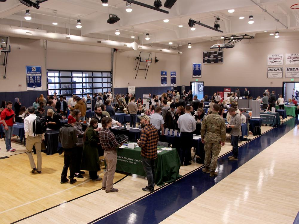 A full gym floor at the PAW Center, with the floor being full of employers, students, alumni and community members during the career fair.