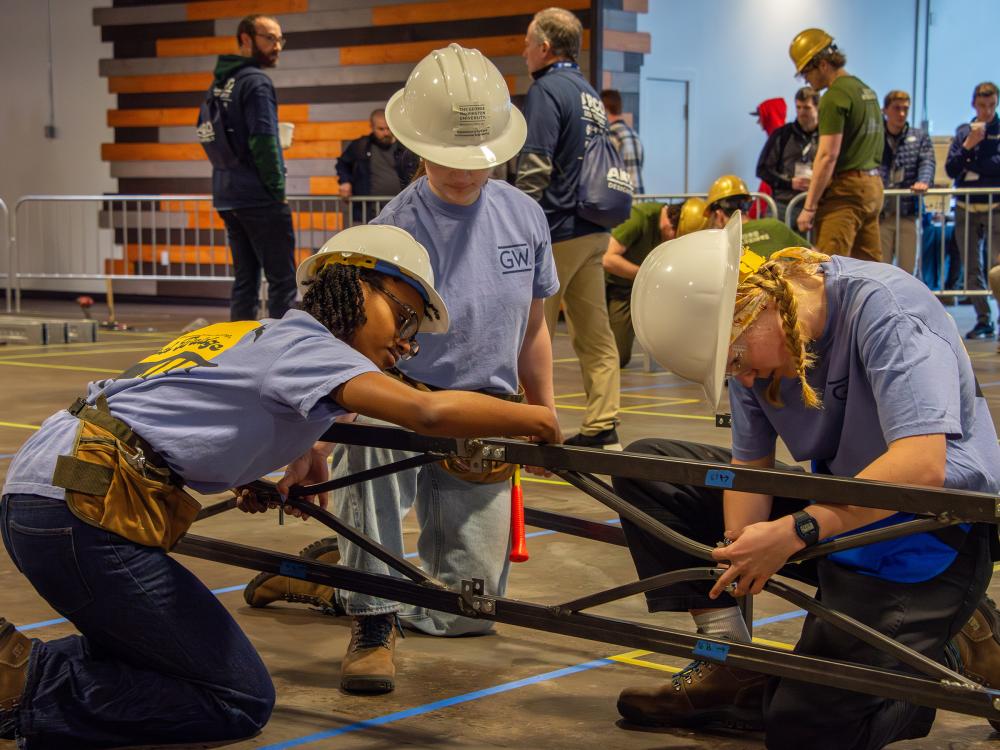 students working on a miniature steel bridge for the competition