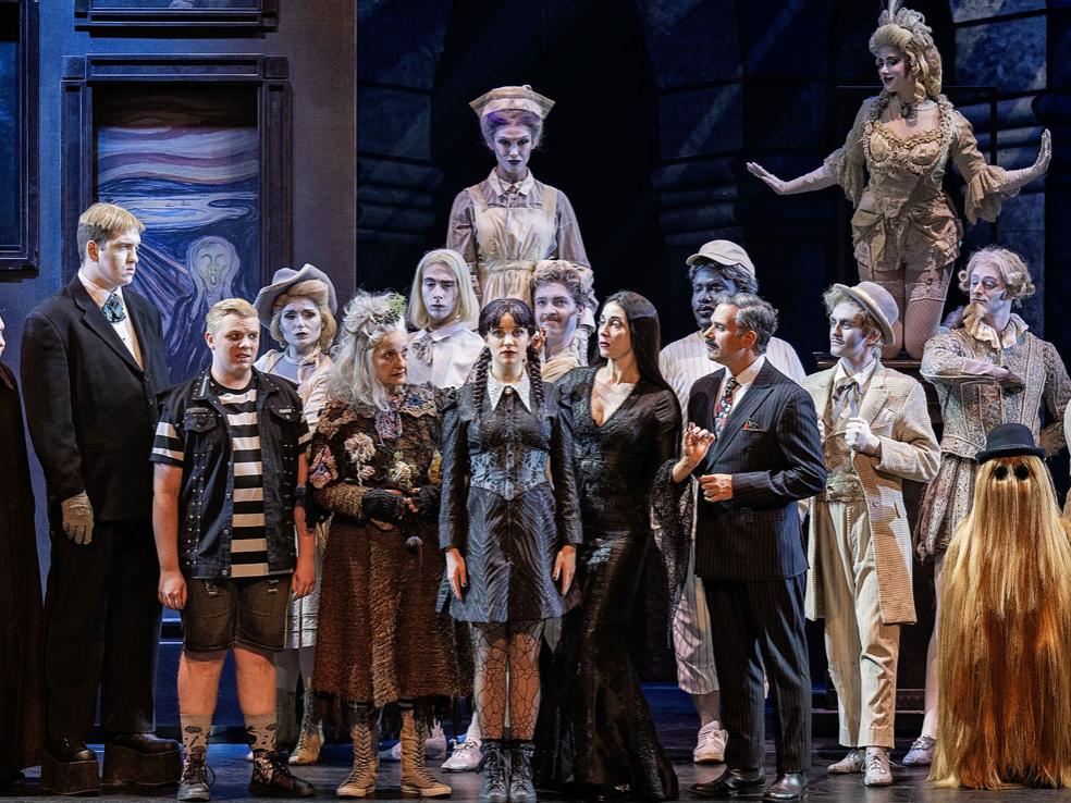 A diverse cast of actors dressed in dark, gothic, and monstrous costumes pose for a family portrait.