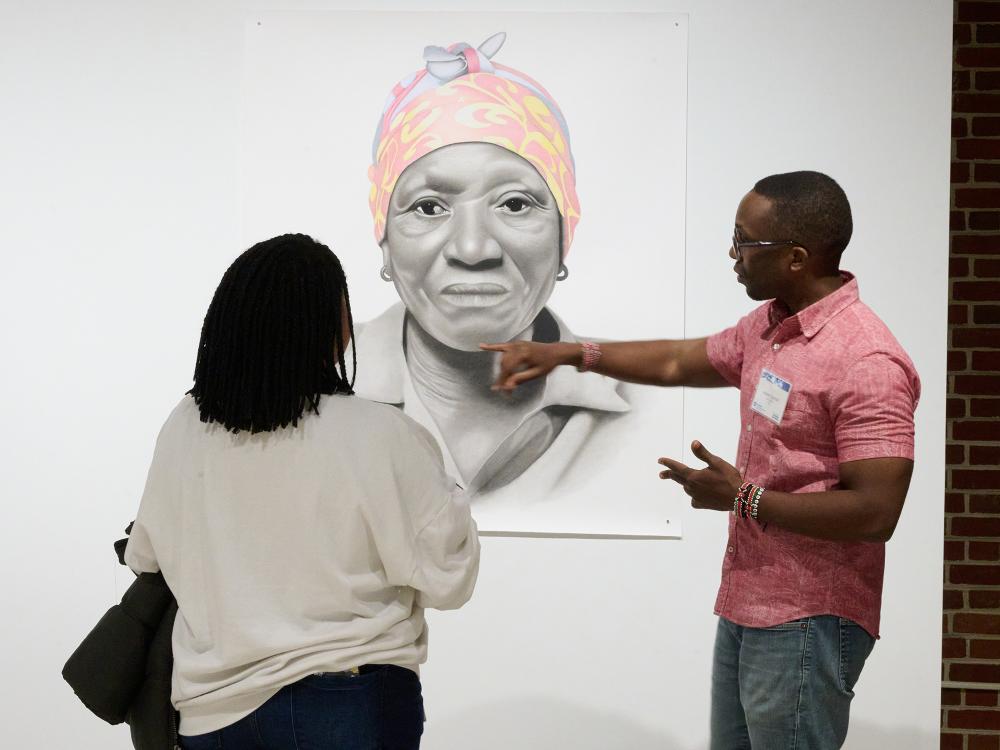 man pointing to artwork on wall while a woman watches