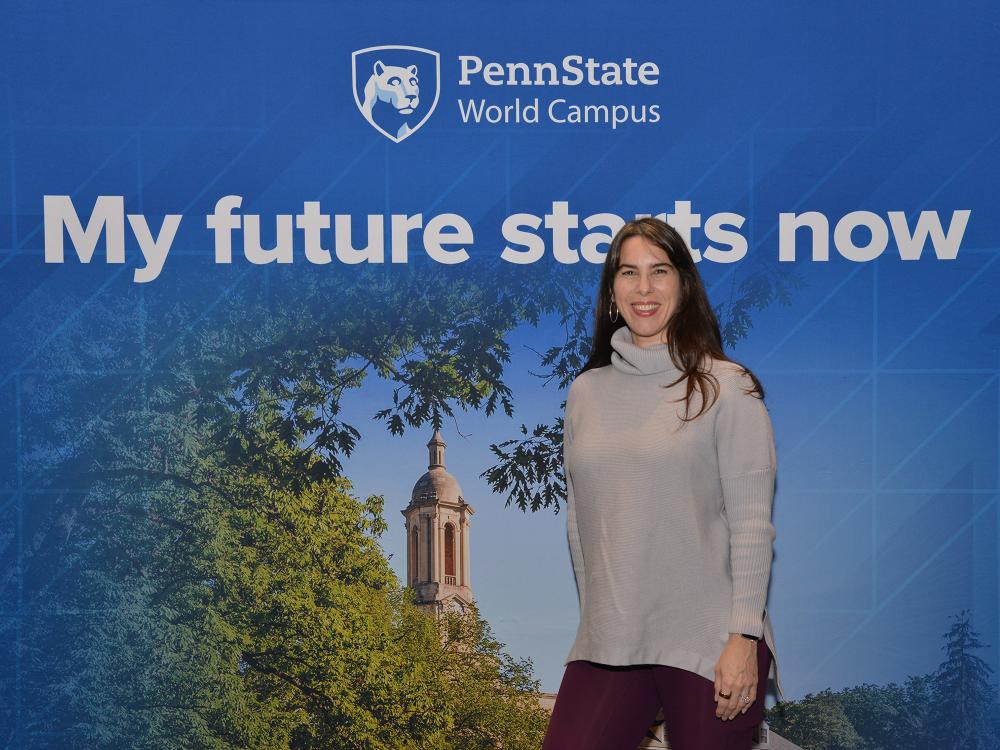 A woman stands in front of a Penn State photo background.