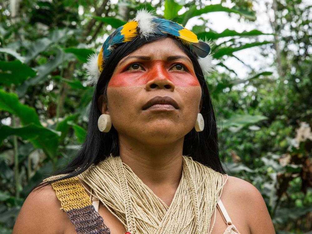 Indigenous woman with face paint standing in the forest