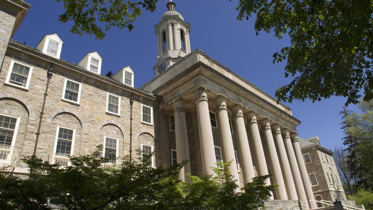 Old Main on a beautiful sunny day surrounded by green foliage and blue sky