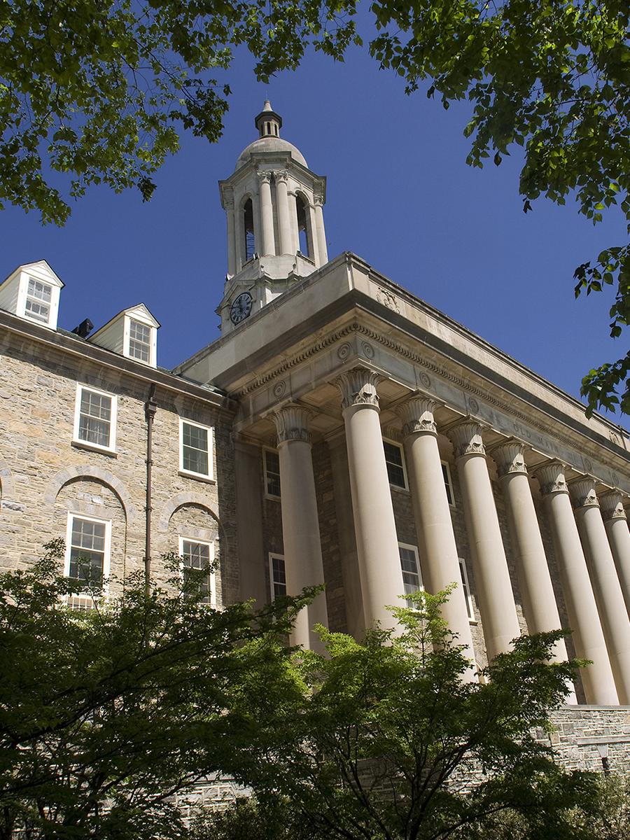 Old Main on a beautiful sunny day surrounded by green foliage and blue sky