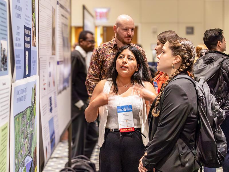 A woman discusses her research with a poster session attendee