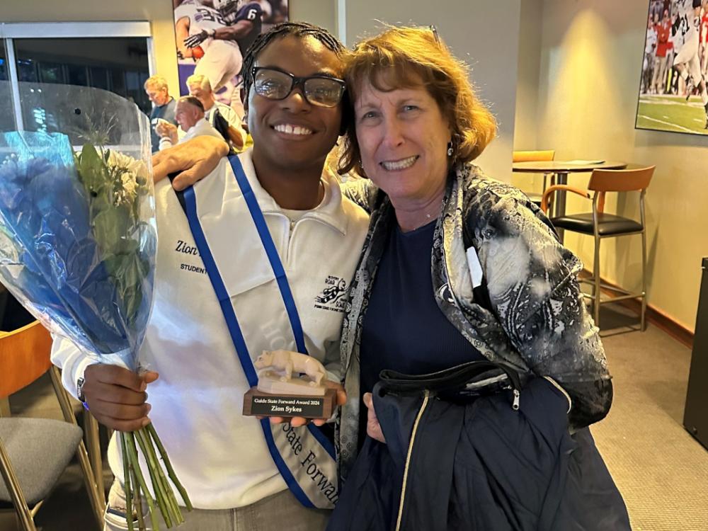 Sally Bedrick stands with her arm around Zion Sykes as the two pose for a photograph.