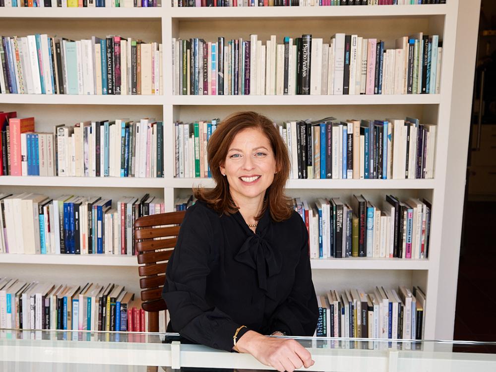 Image of Sara Guyer, dean at University of California Berkley, standing in front of bookshelf
