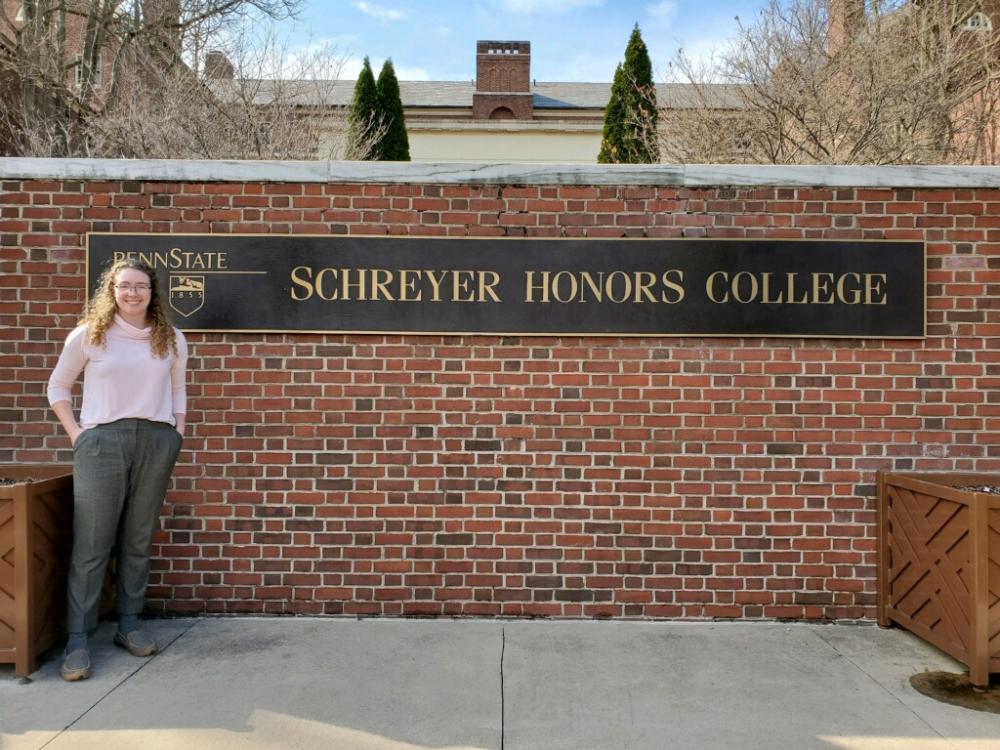 Landis Crawford stands in front of Schreyer Honors College sign
