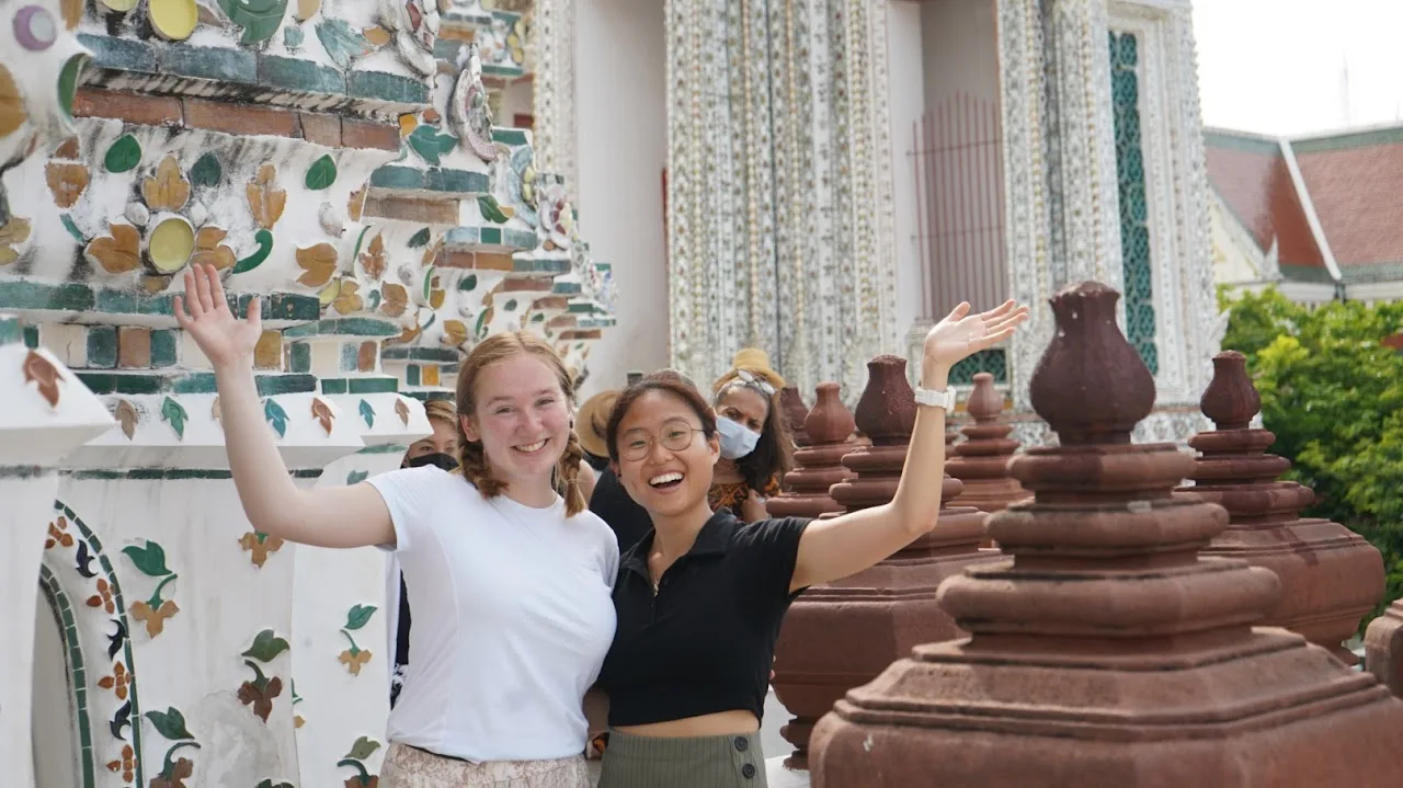 Two students waving to the camera