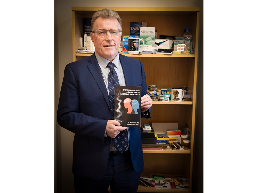 Person in a suit standing in front of bookshelf